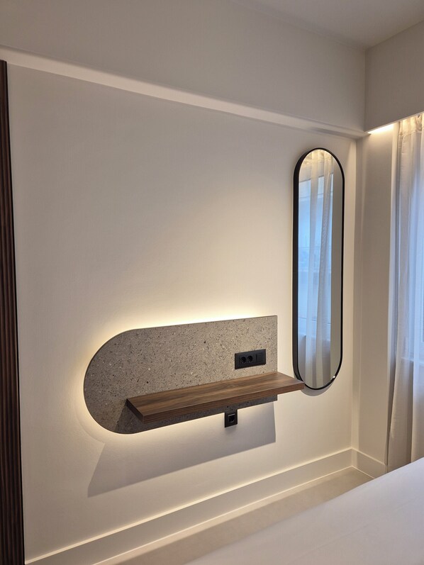 A modern bathroom with a built-in shelf, a wall-mounted mirror, and a shower area. - Shape Suites Athens (Athens)
