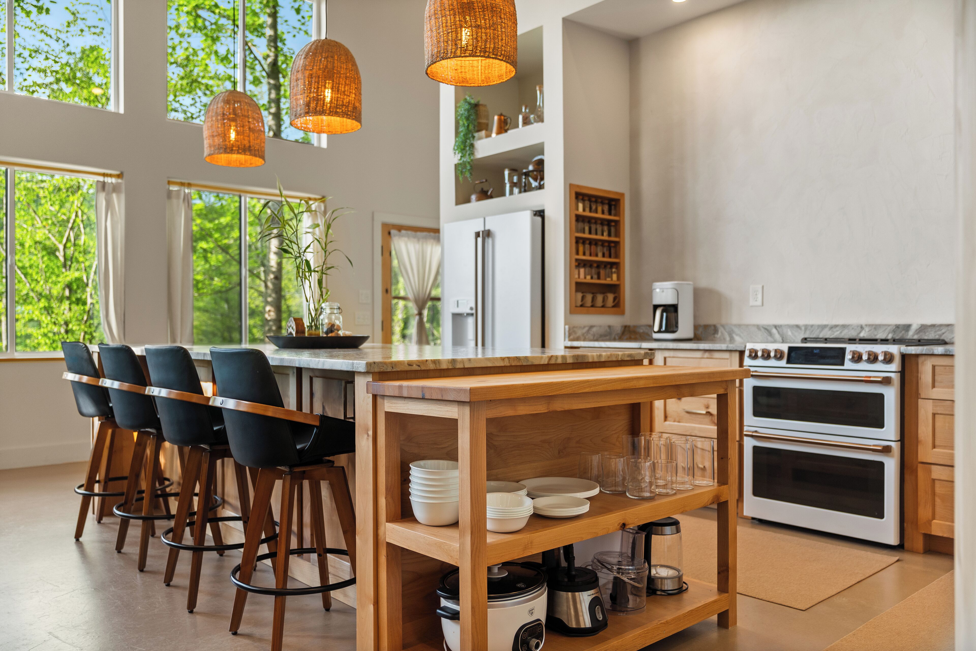 A modern kitchen with a central island, bar stools, a coffee machine, and a stove.