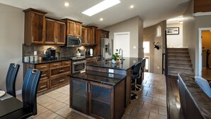 A modern kitchen with wooden cabinets, stainless steel appliances, and a large island. - Opulent Oasis luxurious getaway near the coulees (Lethbridge)