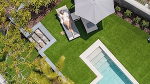 A pool area with a lounge chair, a small pool, and surrounding greenery.
