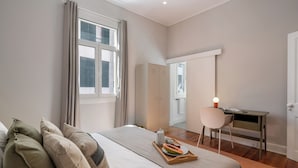 A bedroom with a bed, a desk, and a wardrobe.