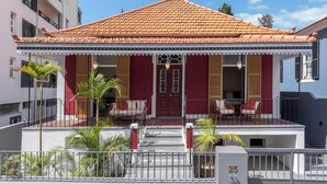 A two-story building with a red-tiled roof, a balcony with outdoor seating, and a number '25' sign on the facade.