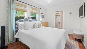 Un dormitorio con una cama grande, una mesita de noche, una lámpara, un armario y una ventana con cortinas.
