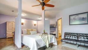 A bedroom with a bed, a sofa, a ceiling fan, and a painting on the wall. - Villa 101 · Peaceful River Views · Steps to Water (Glen Rose)