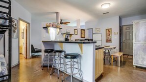 A compact kitchen with a central island, bar stools, and a dining area. - Villa 101 · Peaceful River Views · Steps to Water (Glen Rose)