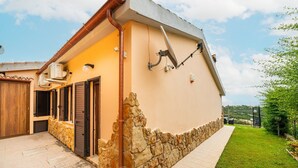 Una casa de dos pisos con base de piedra, un patio adoquinado y un pequeño jardín.