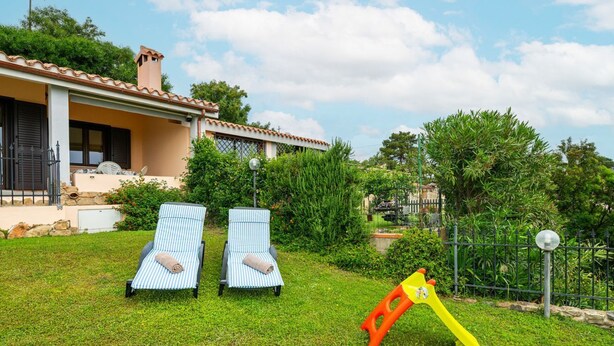 Una casa con jardín, dos sillones de descanso y un columpio.