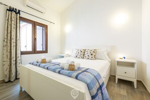 Une chambre à coucher bien rangée, avec un lit, des tables de chevet et une fenêtre avec des rideaux.