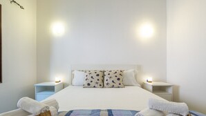 Un lit bien fait, recouvert d’une couvre-lit à carreaux bleus et blancs, avec deux oreillers assortis et deux lampes de chevet.