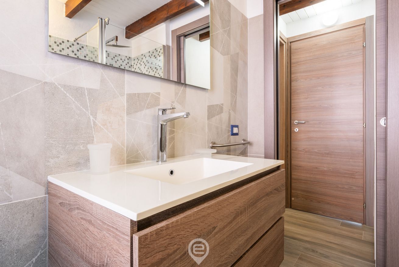 A modern bathroom with a large sink, a mirror, and a wooden vanity.