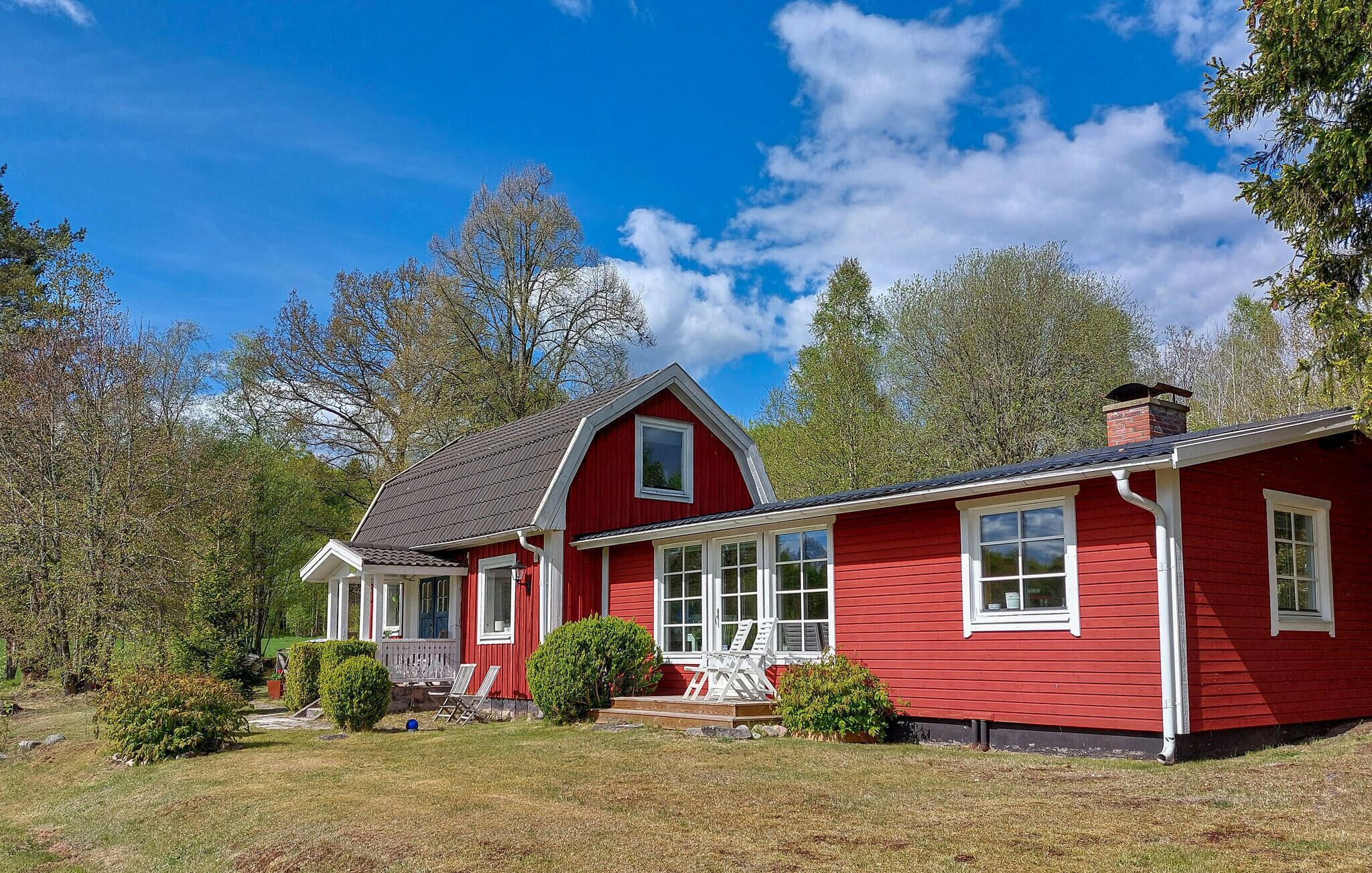 A red house with a porch, a chimney, and a large window.