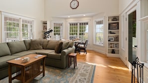 A spacious living room with a sectional sofa, a wooden coffee table, and a dining area with a table and chairs.