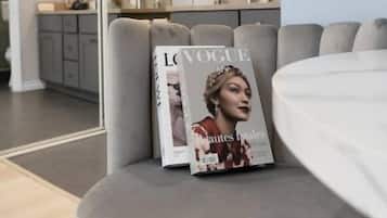 Een moderne woonkamer met een grijze bank, een tijdschrift op de leuning en een televisie aan de muur.