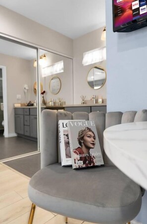 Un salón moderno con un sofá gris, una revista en el reposabrazos y un televisor montado en la pared.