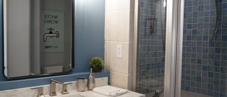 Une salle de bain avec un miroir, un lavabo et une douche.