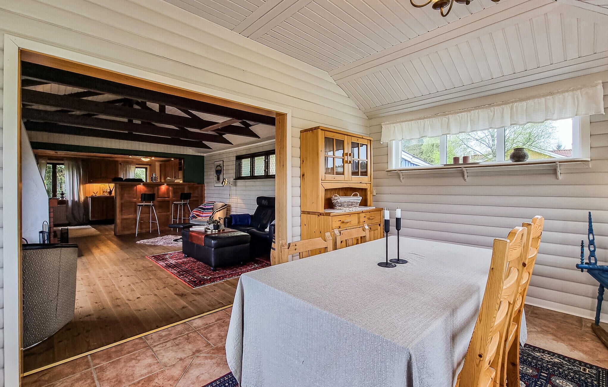 A spacious living area with a dining table, wooden cabinets, and a kitchen in the background.