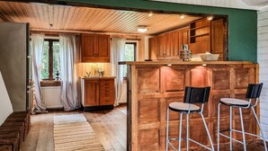 Una cucina rustica con mobili in legno, una zona bar con sgabelli e vista sull'esterno attraverso una finestra.