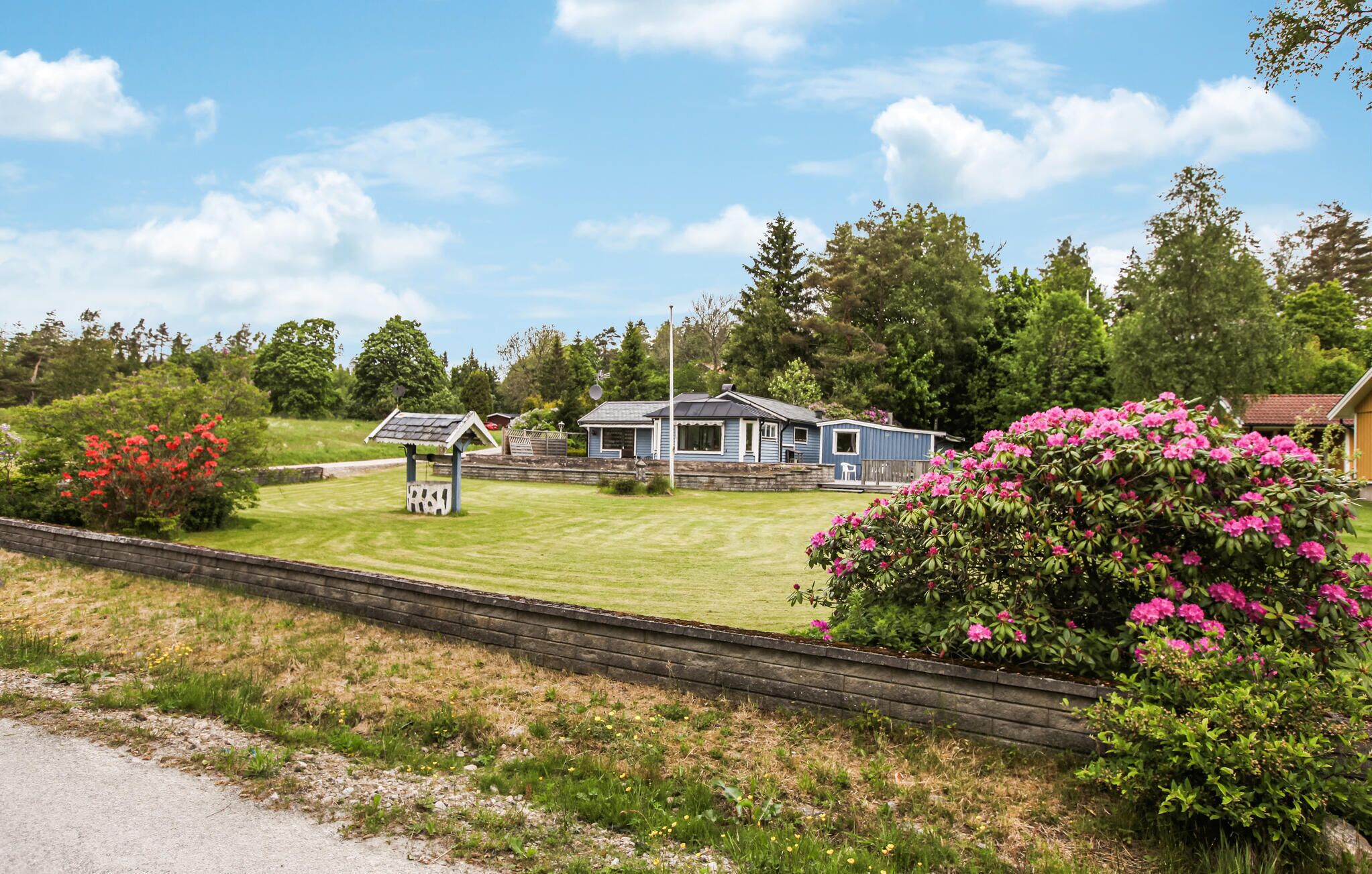 Ett litet hus i ett våningsplan med ett sluttande tak, en inhägnad trädgård och en välskött gräsmatta.