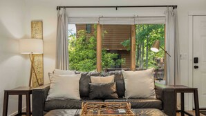 A modern living room with a leather sofa, a woven coffee table, and a map on the wall. - Cozy Cottage 2 min to WNC AG Center Pet Friendly (Fletcher)