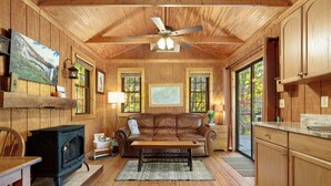 Ein gemütliches Blockhaus-Interieur mit Holzwänden, Kamin, einer Couch und einem Essbereich.