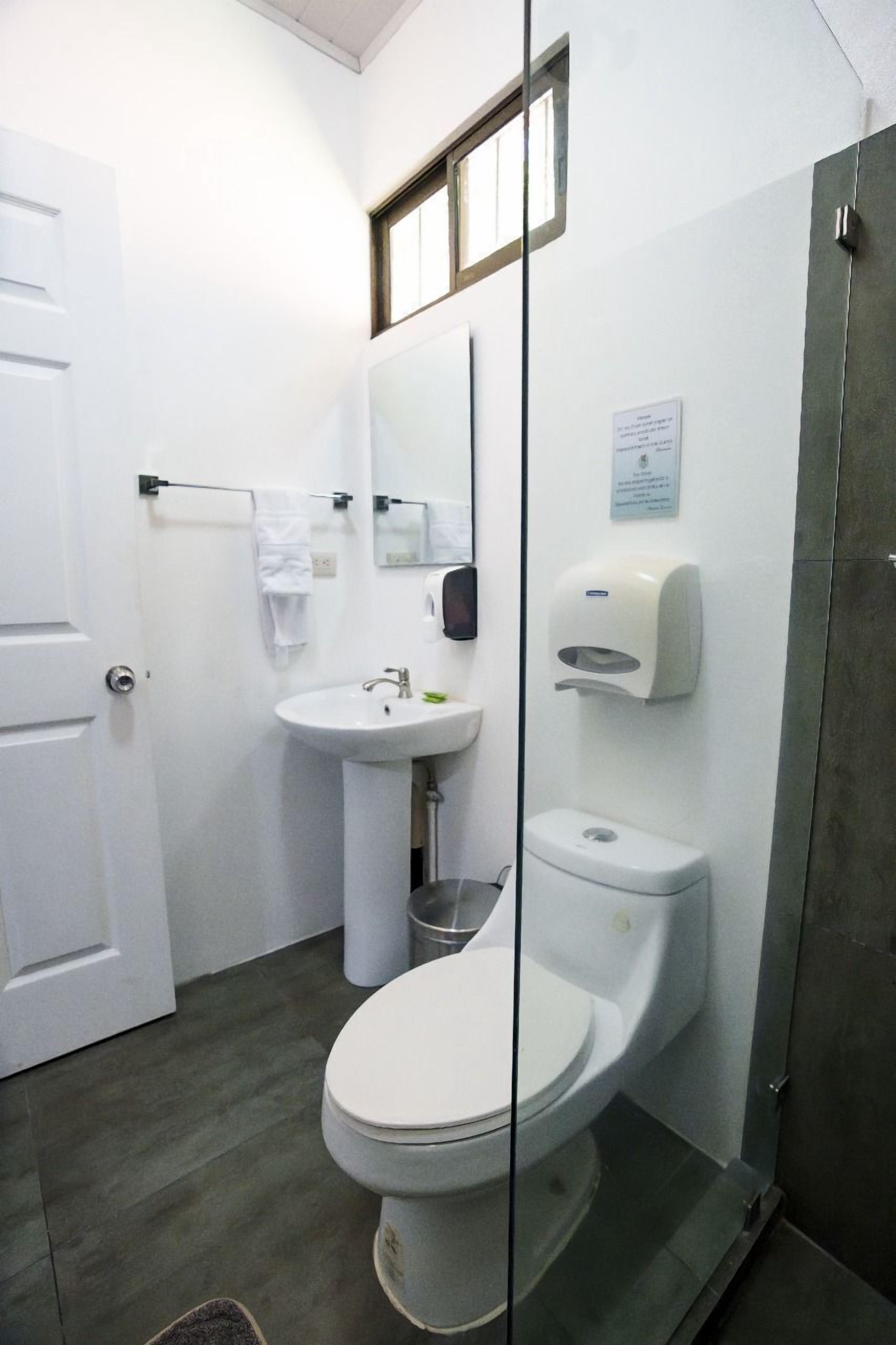 A bathroom with a toilet, sink, and hand dryer.