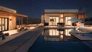 A modern house with a swimming pool, outdoor seating, and a covered patio area.