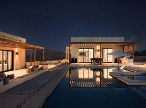 A modern house with a swimming pool, outdoor seating, and a covered patio area.