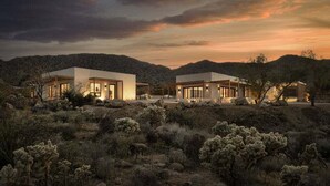 A desert landscape with modern, light-colored buildings featuring large windows and a flat roof design.