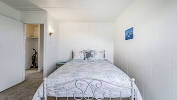 A bedroom with a bed, a nightstand, a wall-mounted light, and a painting.