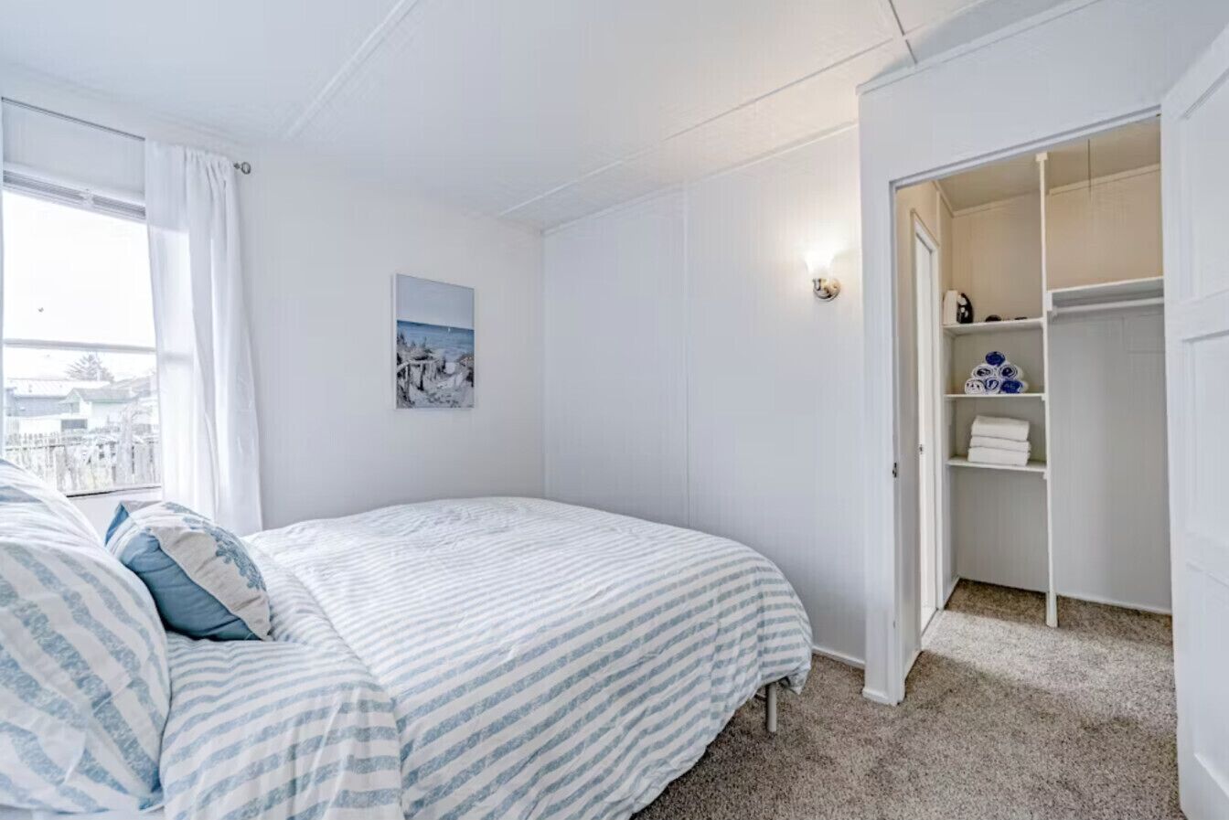 A bedroom with a bed, a closet, and a window with curtains.