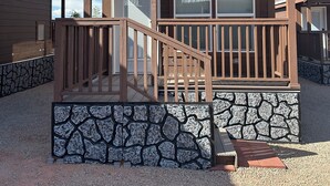 Een houten chalet met een stenen fundering, een houten terras en een overdekte veranda.