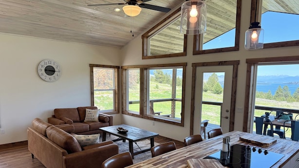 A modern kitchen with a wooden island, large windows, and a view of the outdoors. - Wild Horse Sunrise at Flathead Lake (Big Arm)