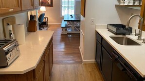 Eine kompakte Küche mit Holzausbau, einer Arbeitsplatte mit Toaster, Spüle und einer Essecke mit Tisch und Stühlen.