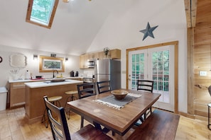 Enjoy cooking in this well-equipped kitchen with a central island, bar stools, and a large window offering a view of the outdoors.