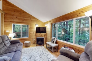 Cozy cabin with a fireplace, large window, and comfortable seating area.