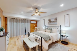 Relax in a spacious bedroom with a large bed, ceiling fan, and natural light pouring in through the large window.