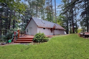 Situated in a forested area, this single-story house features a front porch and a well-maintained lawn.