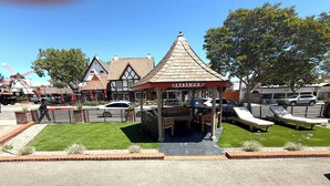 A gazebo with a red roof and the name 'LYSTHUS' on it, surrounded by a small lawn and seating area.