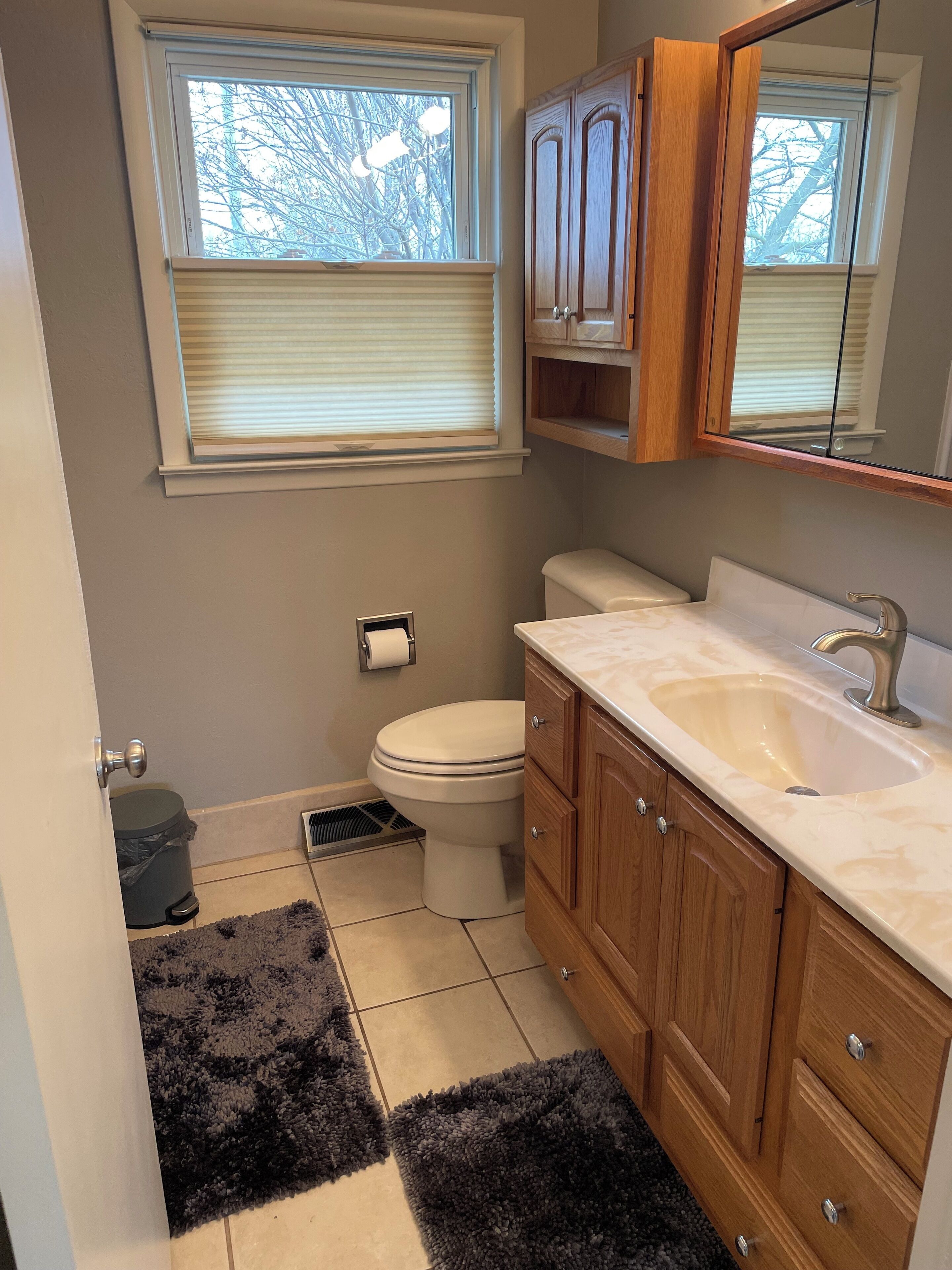 A compact bathroom with a toilet, sink, and wooden cabinets.