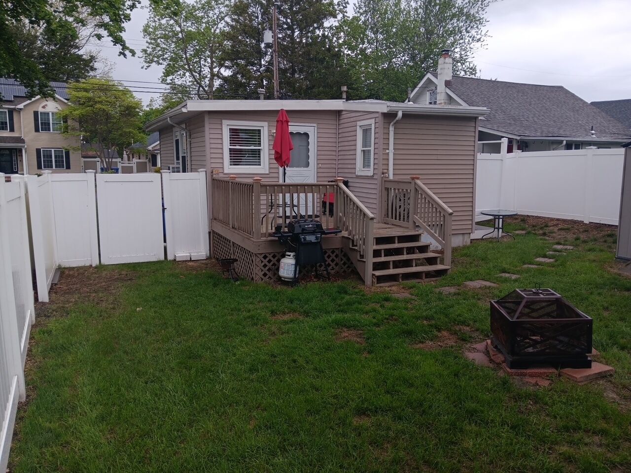 A single-story house with a deck, a small patio, and a fenced yard.