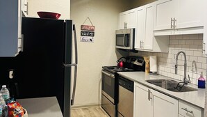 A modern kitchen with white cabinets, stainless steel appliances, and a microwave. - 2-bedroom apartment next to Brave's Stadium (Smyrna)