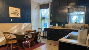 A modern kitchen with dark cabinets, a dining area with wooden chairs, and a large window providing natural light.