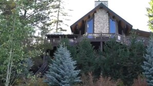 Ein großes, mehrgeschossiges Holzhaus mit Steinverkleidung und einem Balkon.