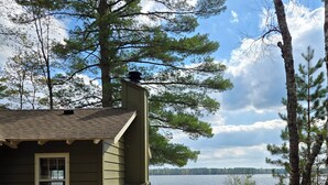 A cabin with a dock extending into a lake, surrounded by trees. - Family and pet friendly, waterfront cabin on Lost Lake, with private dock (Saint Germain)