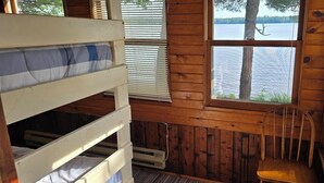 A cabin with a bunk bed, a wooden chair, and a window overlooking a lake. - Family and pet friendly, waterfront cabin on Lost Lake, with private dock (Saint Germain)