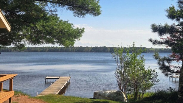 A lakeside view with a wooden dock extending into the water, surrounded by trees and a clear sky. - Family and pet friendly, waterfront cabin on Lost Lake, with private dock (Saint Germain)