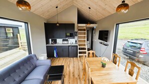 A compact living space with a sofa, dining table, and kitchen area. - Cosy Northern Ligths Cabin with hot tub and magical views on the Golden Circle (Grímsnes- og Grafningshreppur)