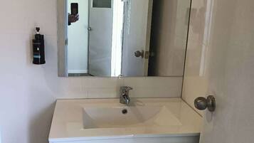 A bathroom with a white sink, a mirror, and a door.