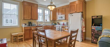 A kitchen with wooden cabinets, a dining table with chairs, a microwave, and a refrigerator.
