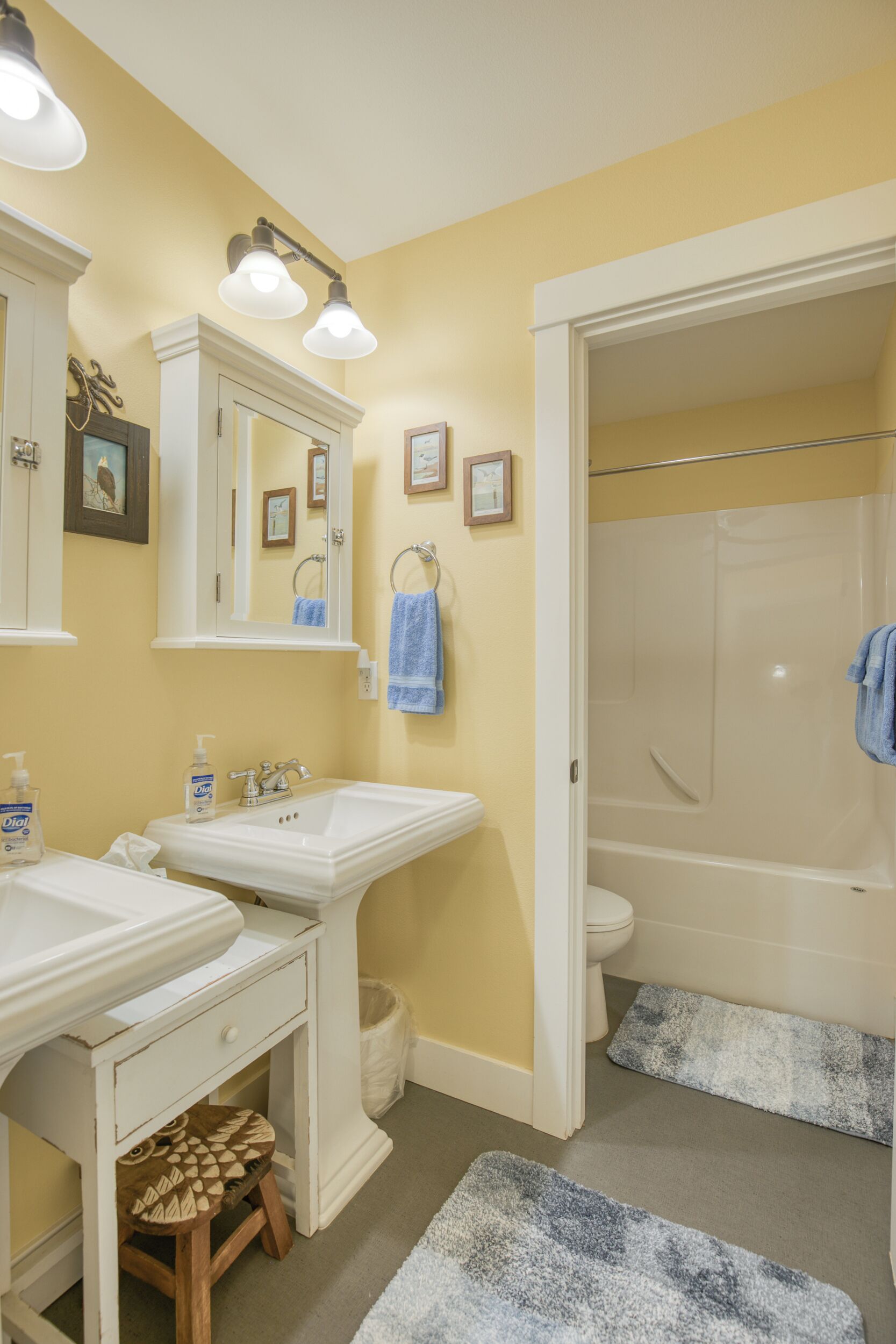 A bathroom with two sinks, a mirror, a toilet, and a shower.